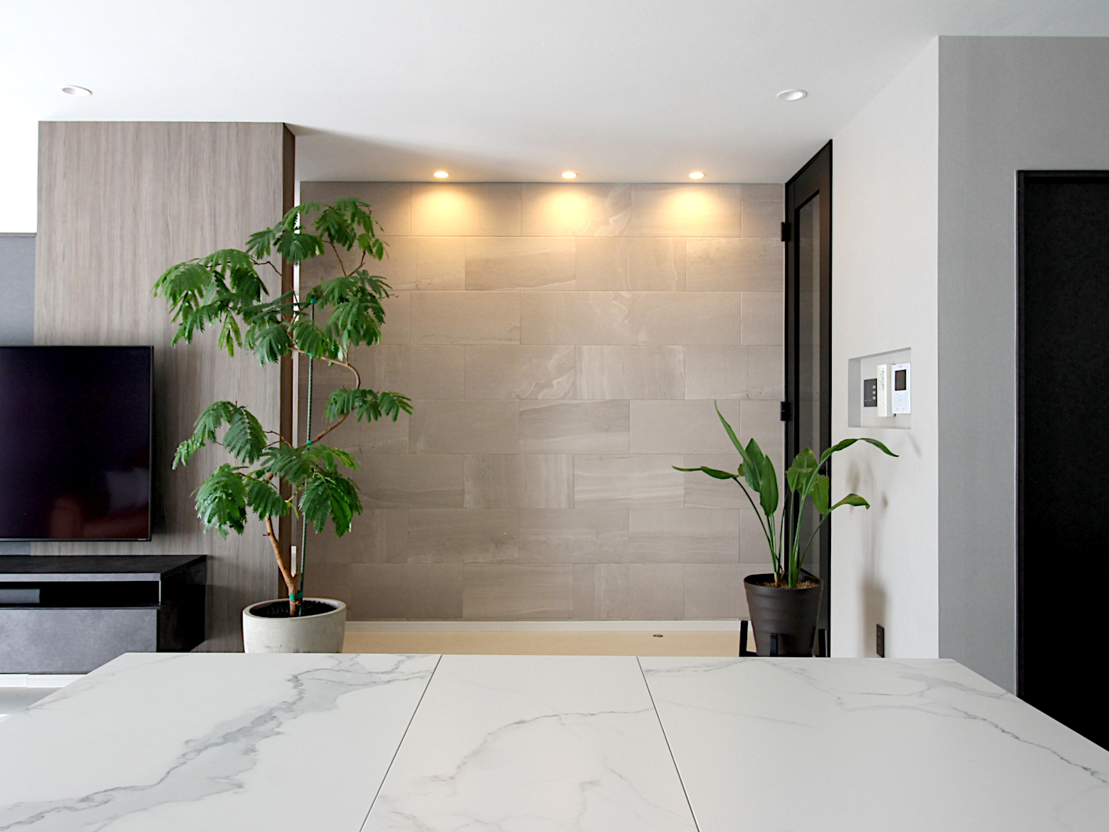 エコカラットストーングレース ベージュと木目調壁を組み合わせ、間接照明が柔らかく照らす