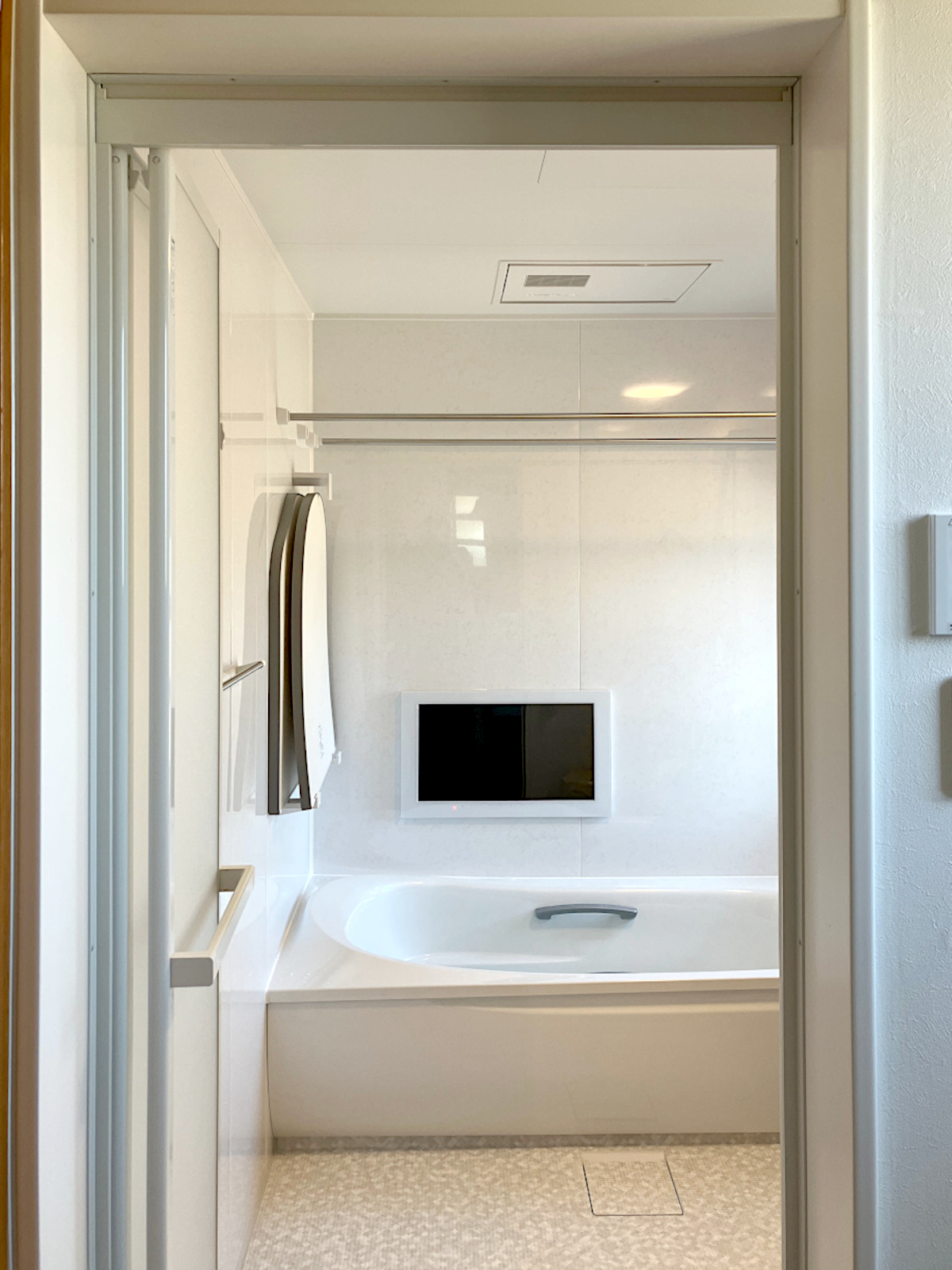 ほっカラリ床ホワイトラグ調で足元も快適。浴室暖房乾燥機と浴室テレビを備えた、ホテルライクなバス空間のリフォーム事例。