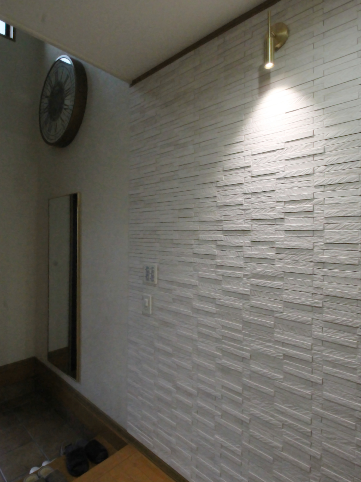 名古屋市の玄関リフォーム事例。LIXILエコカラットプラス ルドラ ホワイトECP2515NET/LDN1を採用。照明がタイルの立体感を引き立てる上質な空間。