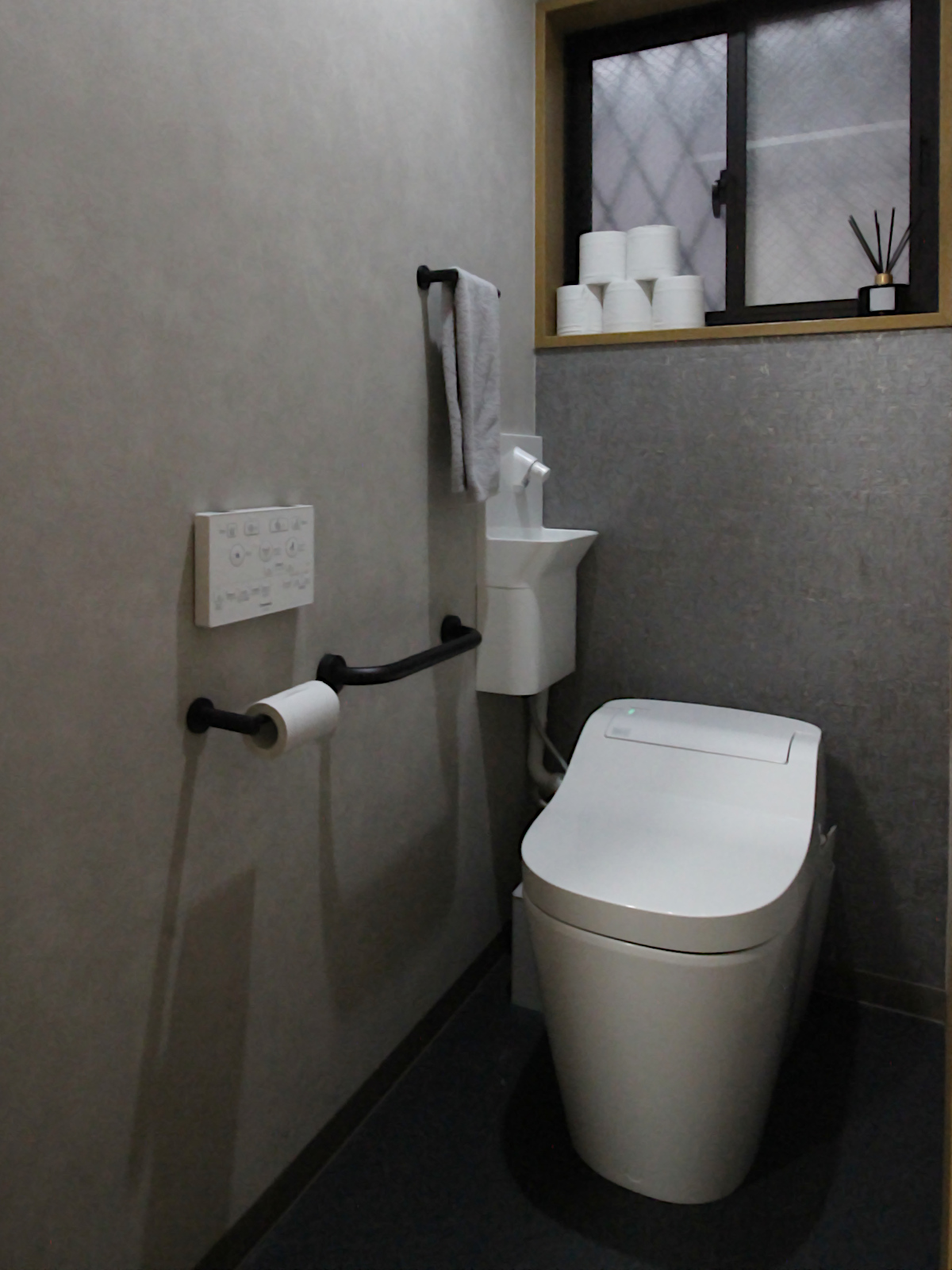 名古屋市の戸建てトイレリフォーム事例。天然コルク素材のアクセント壁が印象的な、落ち着きあるモダン空間。