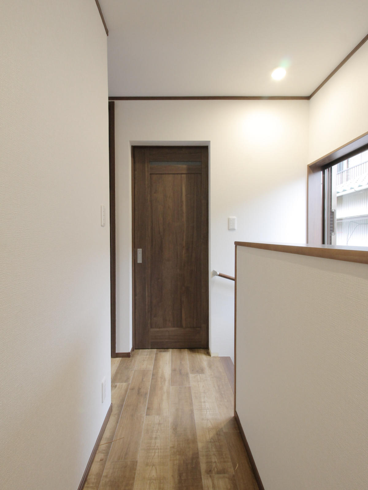 パナソニックのベリティス、ウォルナット柄のドアとサンゲツのフロアタイルWS-2129の明るい木目でまとめた2階ホール。