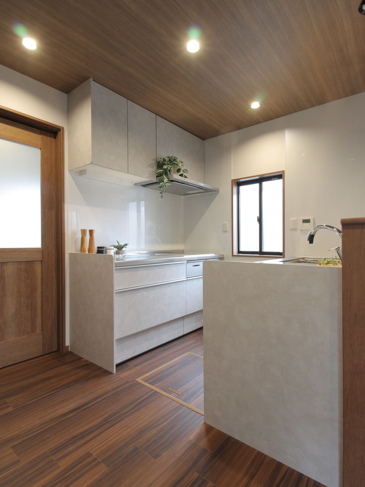 ホワイトスタッコのLIXILシエラS、並列型の対面キッチン。コンロキャビネットは壁付で油汚れの広がりを抑える。