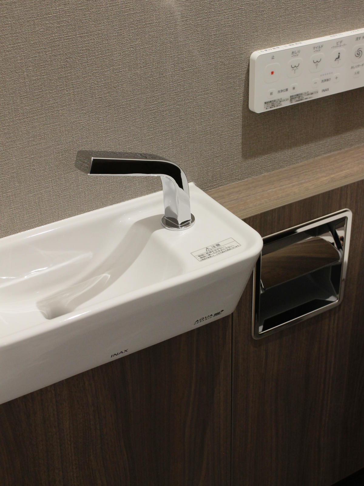 LIXIL・サティスSタイプの手洗器部分。ウォルナットのキャビネットとの調和でデザイン性を高め、アクアセラミックの艶やかさと清潔感が引き立つ。