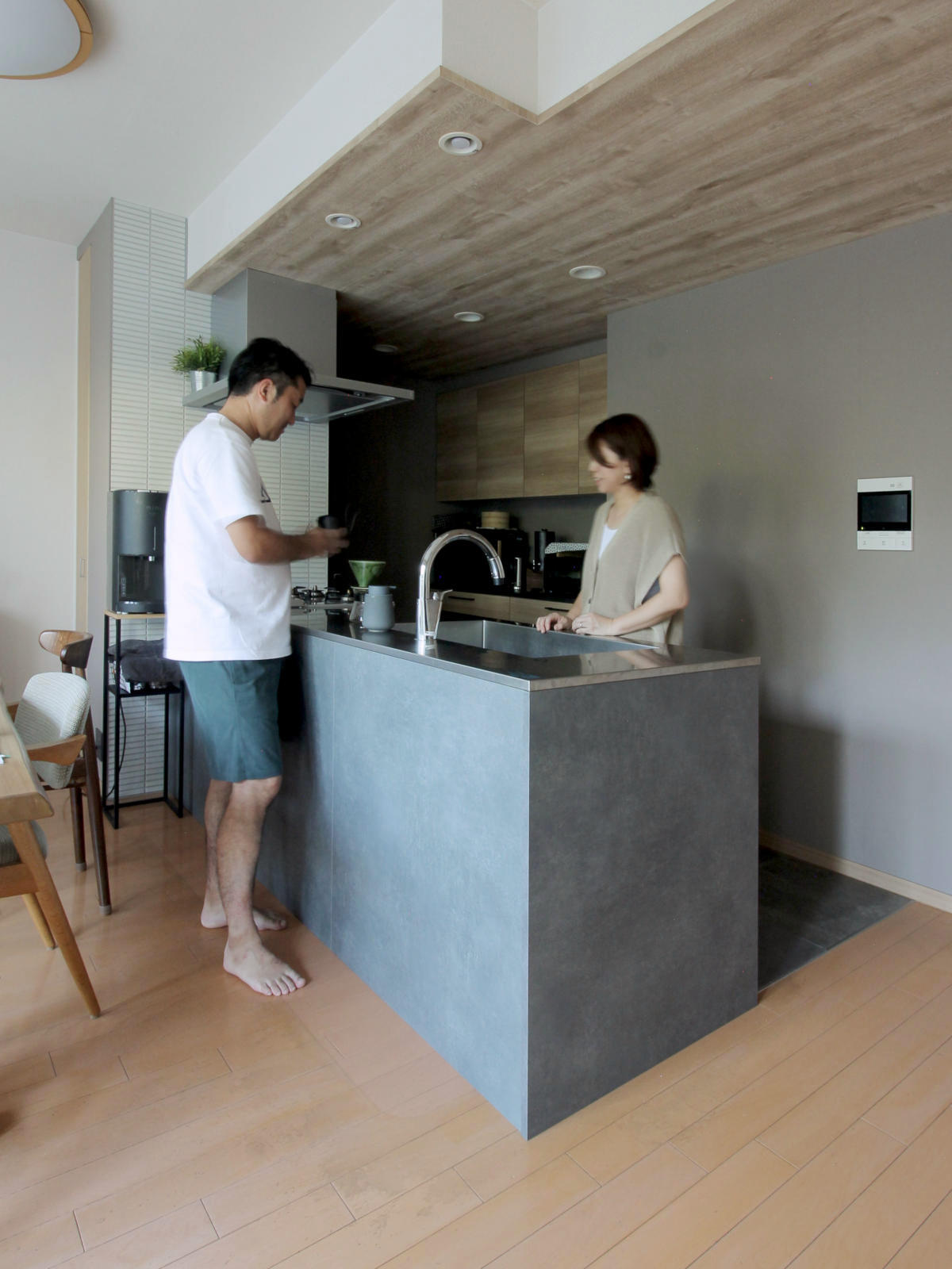 オープンスタイルのキッチンリフォーム。ステンレス天板と木目キャビネットの調和が美しく、会話が弾む空間に。