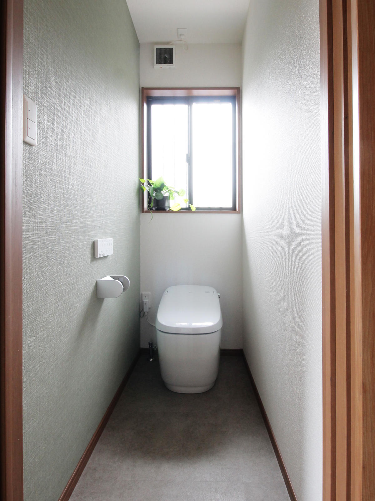 名古屋市西区戸建てリノベーション事例。LIXILサティスGを採用した1階トイレ。グリーンのアクセントクロスRE-55155と木目の建具が調和し、清潔で落ち着きある空間に。