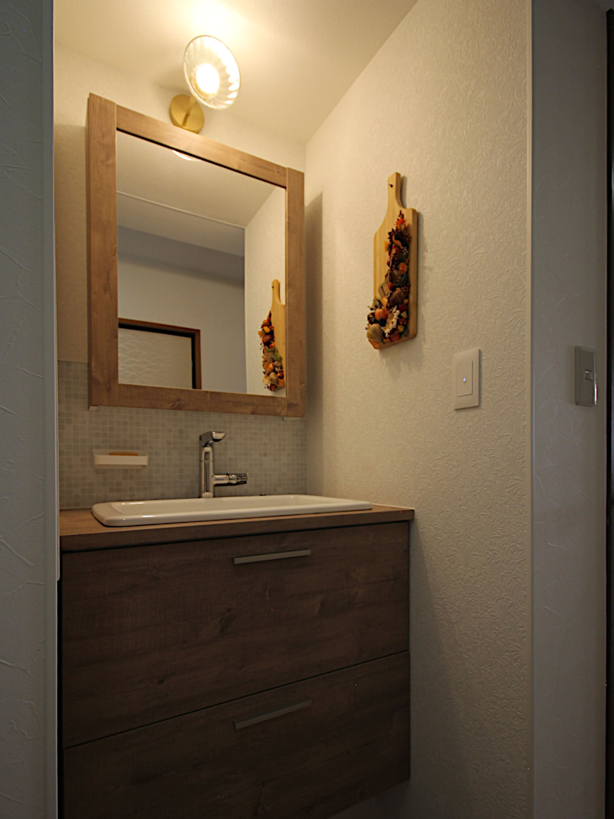 マンションリフォーム事例。TOTOドレーナを採用した洗面化粧台。木目調キャビネットとモザイクタイルの組み合わせで、ナチュラルモダンな洗面空間を演出。