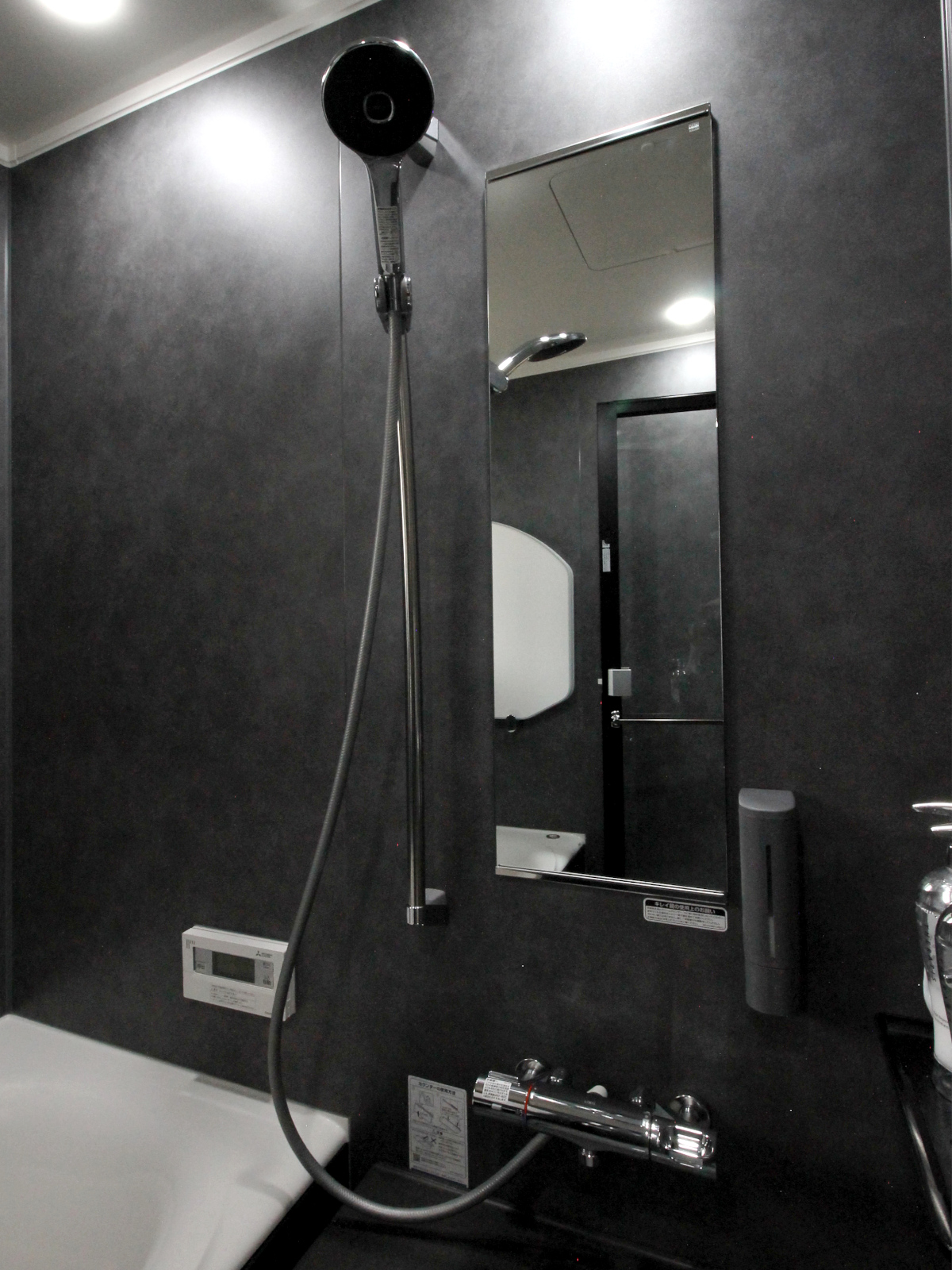 バスリノベーション事例。モルティオダークの壁パネル【HT614】でシックに統一。シンプルなミラーとシャワーでモダンな印象に。