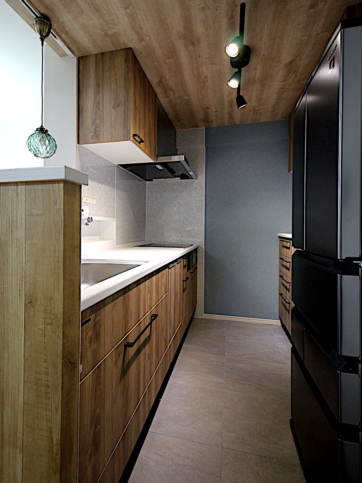 木目天井クロス【FE-74193】を採用したリフォームキッチン。ライティングレールとスポットライトで、温もりと陰影のある空間を演出。