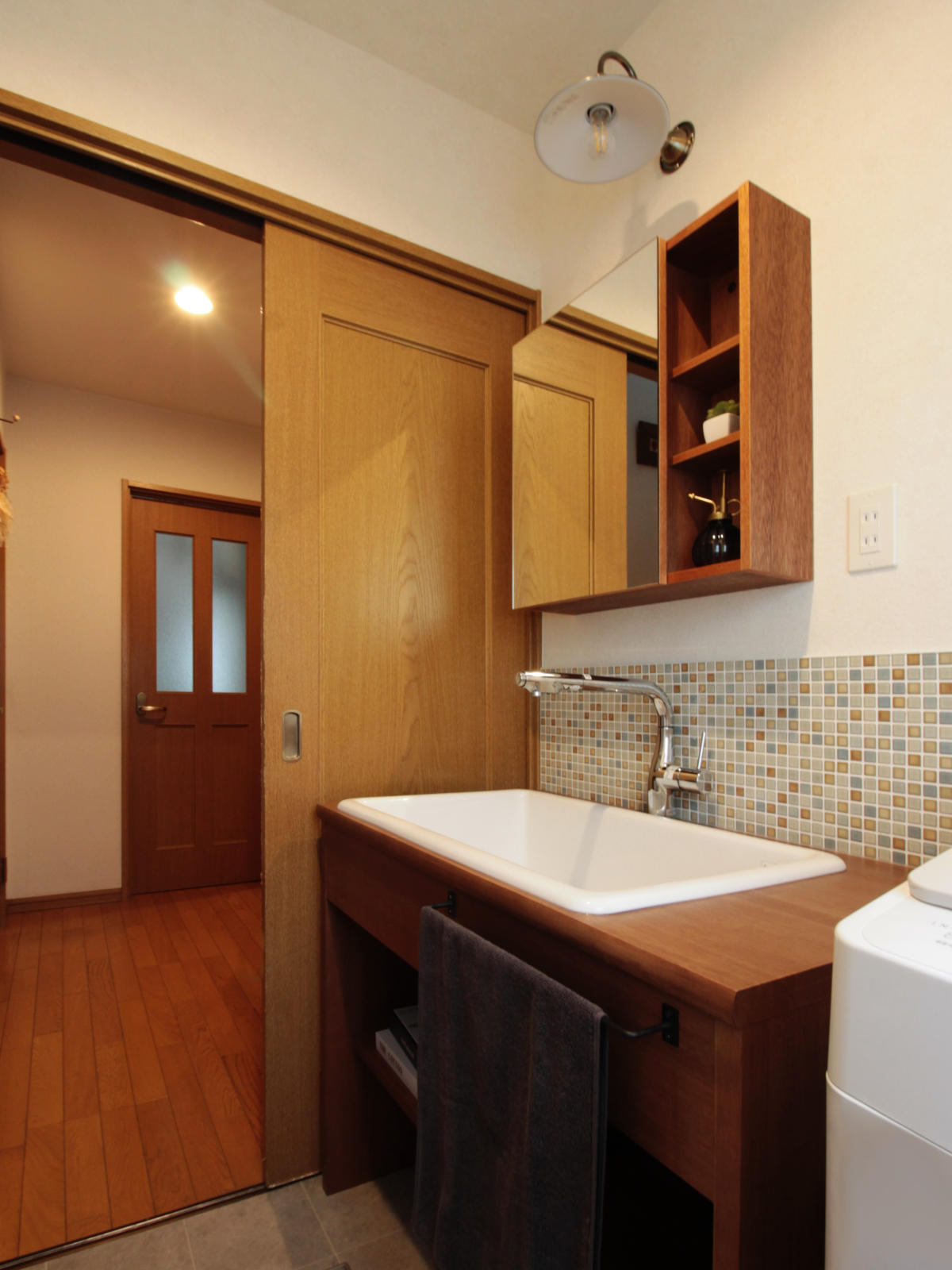 北名古屋市のリノベーション事例。TOTO病院用シンクを採用した造作洗面台。底が平らで愛犬の足洗いやシャンプーも安定。木製カウンターとタイル壁【LIXIL スマートモザイクシートSMTS-630/KLG-11】でナチュラルな雰囲気に。