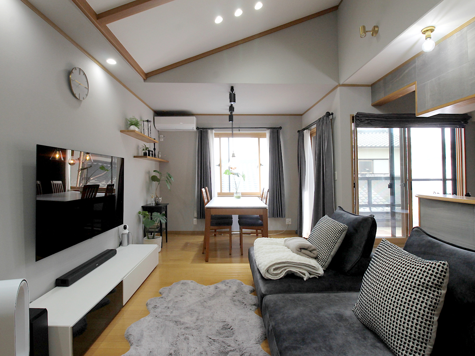 戸建てリビング内装リフォーム。サンゲツクロス【RE5305】でグレートーンに統一。木製建具と観葉植物のコーディネートが心地よい。