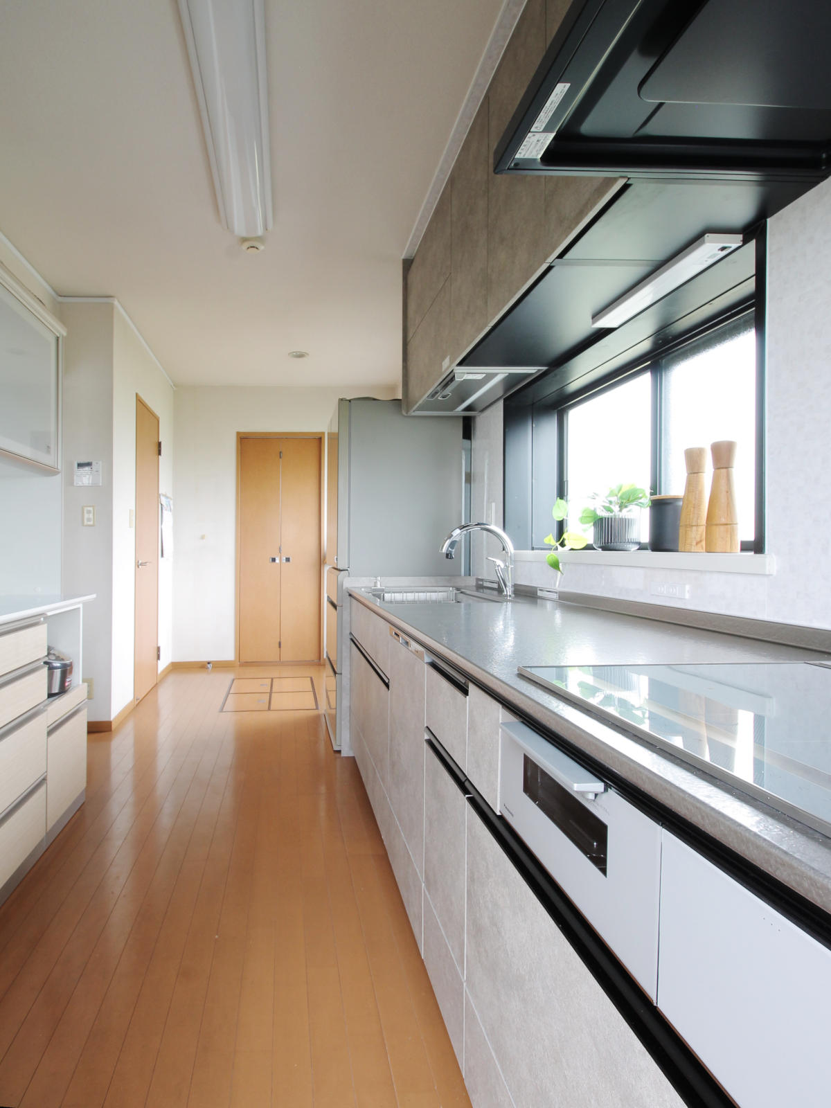 北名古屋市の戸建てのリフォーム事例。クリナップCENTROセントロW2700を中心に、乾燥機能付き電動昇降吊戸棚をプラス。ロカグレージュの扉カラーとステンレス天板が調和し、動線と収納力を高めたスマートなキッチン空間。