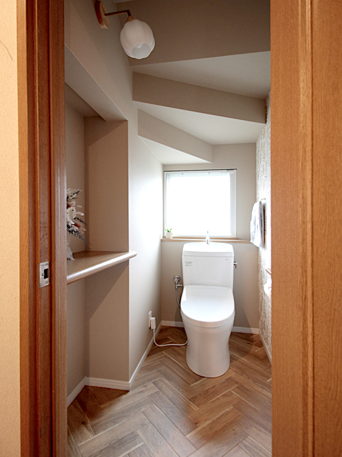 戸建てトイレのリノベーション。花形のガラスシェードが目を引くブラケットライトが、カントリーな雰囲気を演出する北名古屋市の施工事例。