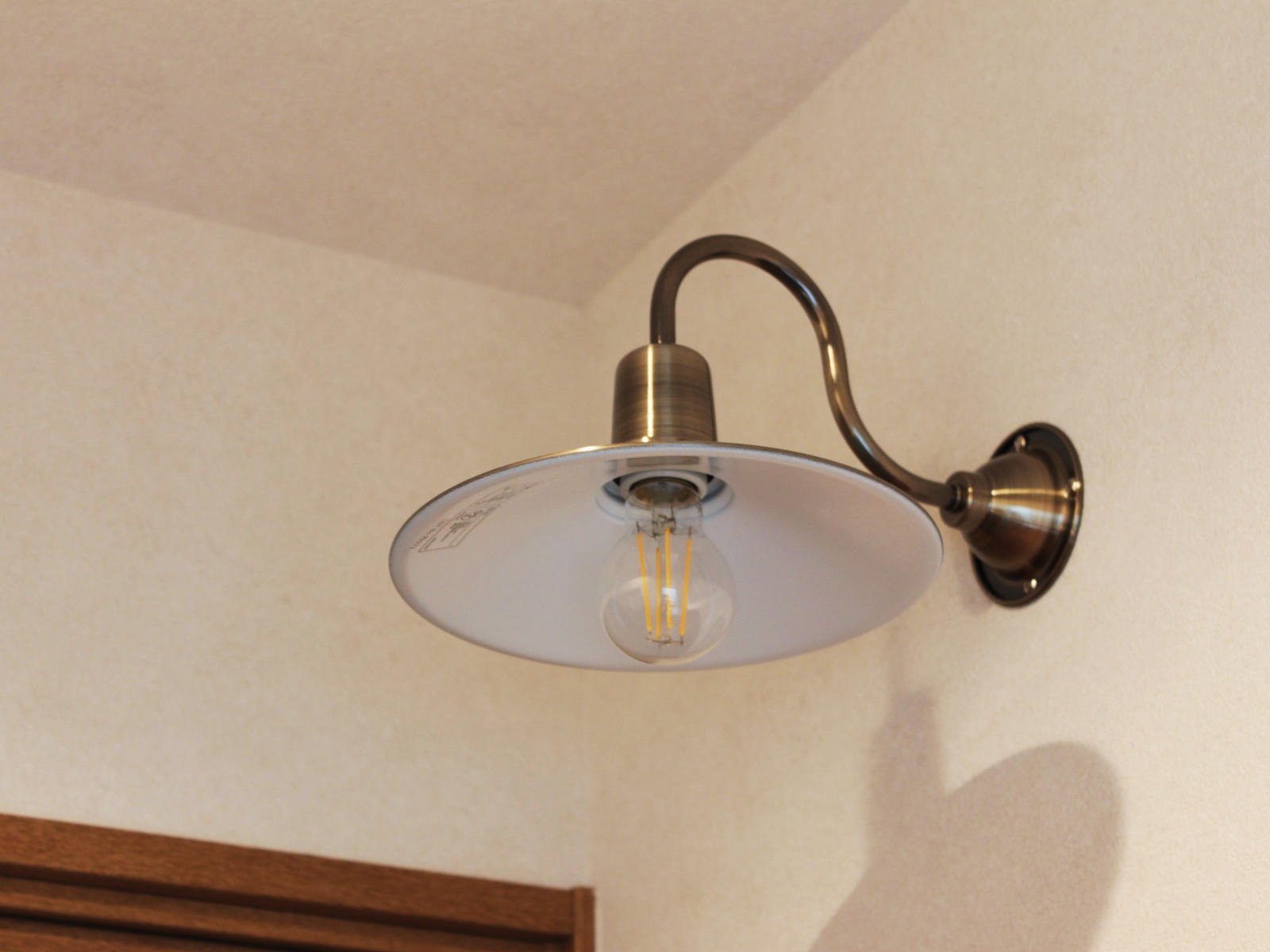 戸建てリノベーション事例。洗面ミラー上に取り付けたブラケットライトが壁面をやさしく照らし、木の建具と調和するあたたかな洗面空間に。